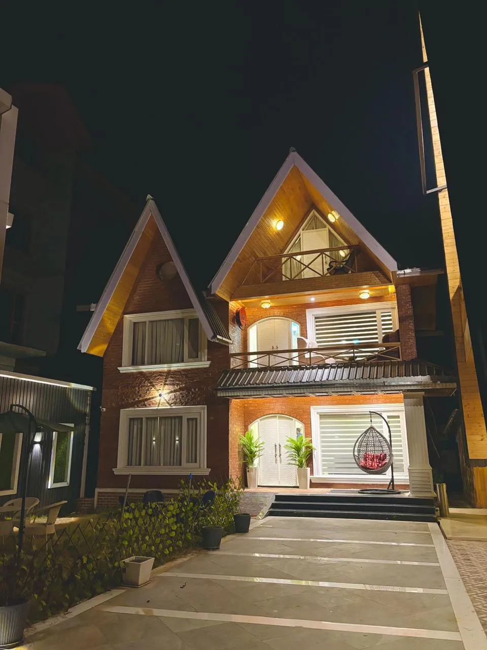 A gabled brick-and-pine chalet lit up at night